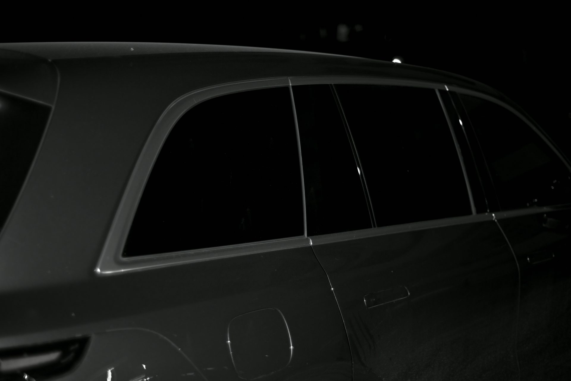 A dark, side profile view of a car.