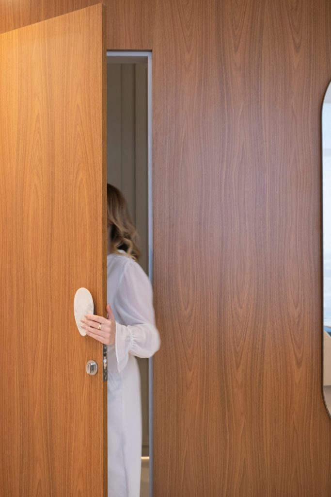 Woman opening a wooden door into a room.